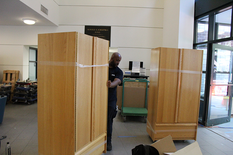 An IRN crew member wheels a wardrobe through the lobby of Schapiro Hall