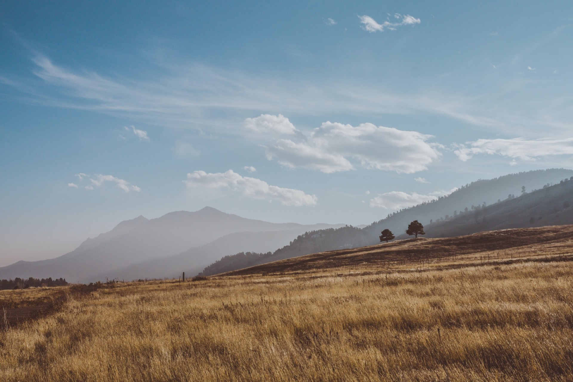 A landscape image of a rolling plain with mountains in the background and a blue sky above