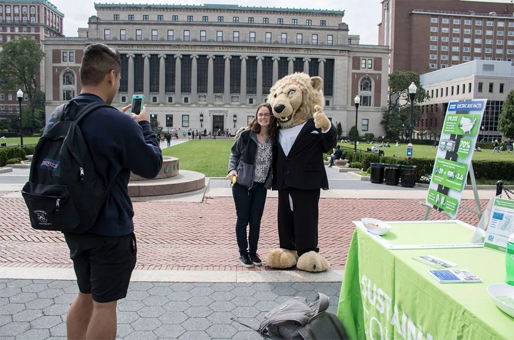 Student taking photo with Roar-ee with Low Library in background