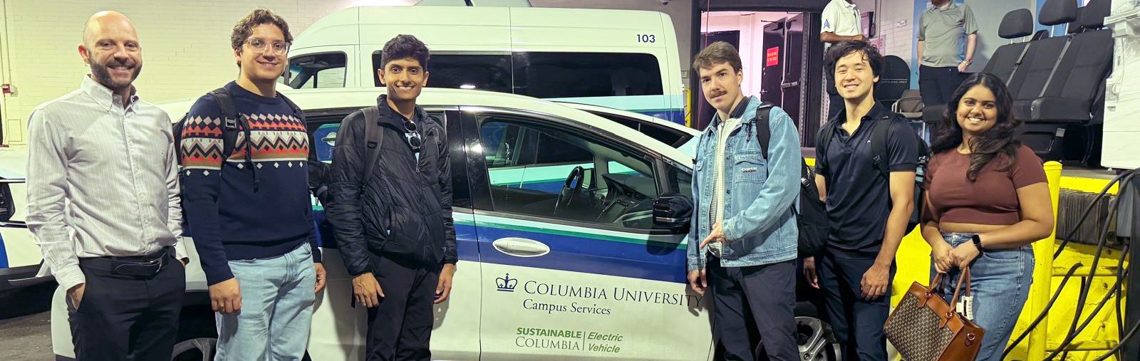 EVO team with Dan Allalemdjian from Office of Sustainability pose in front of an electric Columbia vehicle in the charging garage