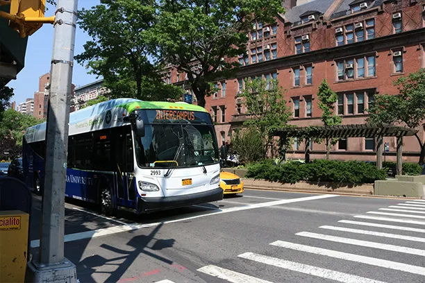 A Columbia electric shuttle bus waits at a red light on Broadway