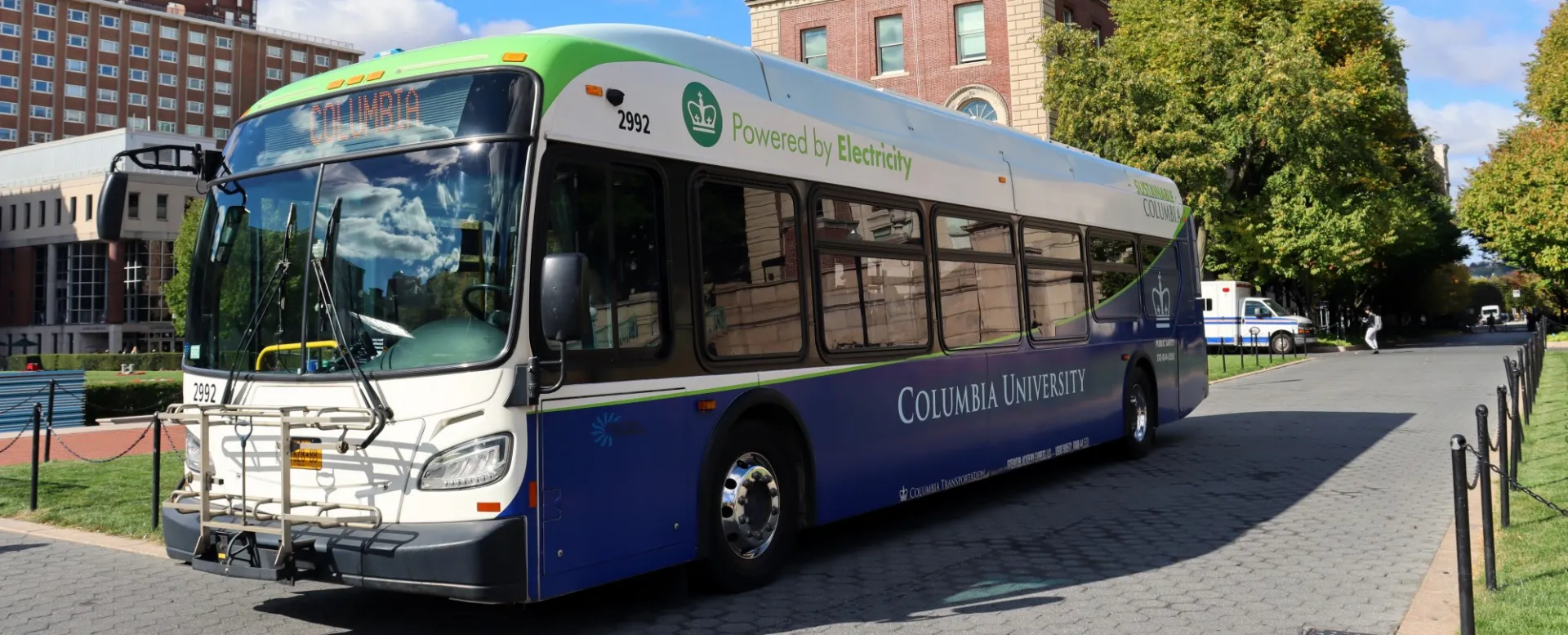 A Columbia electric shuttle bus is parked on College Walk on a sunny day