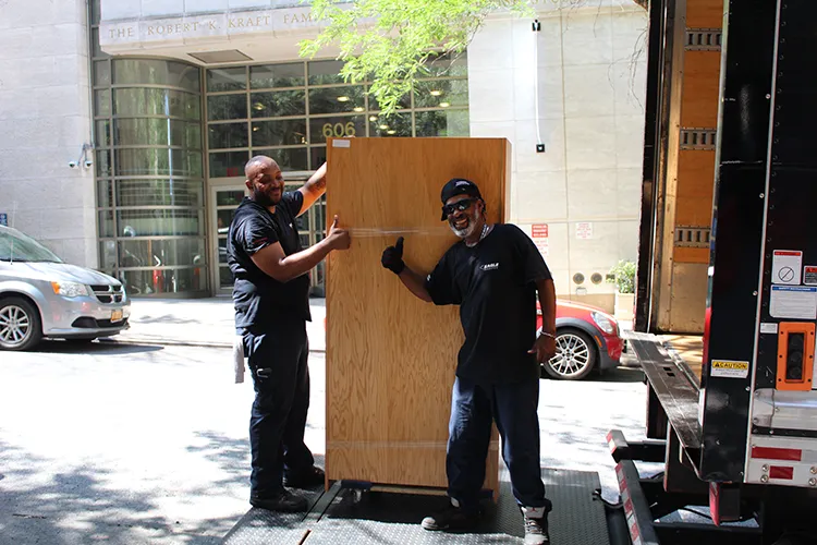 Two IRN crew members maneuver a wardrobe onto a truck