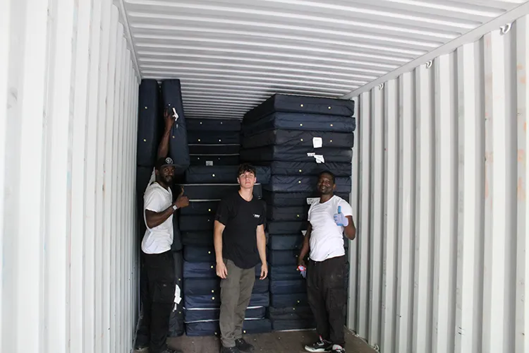Three IRN crew members load mattresses into a truck. This shipment is scheduled for Ukraine.