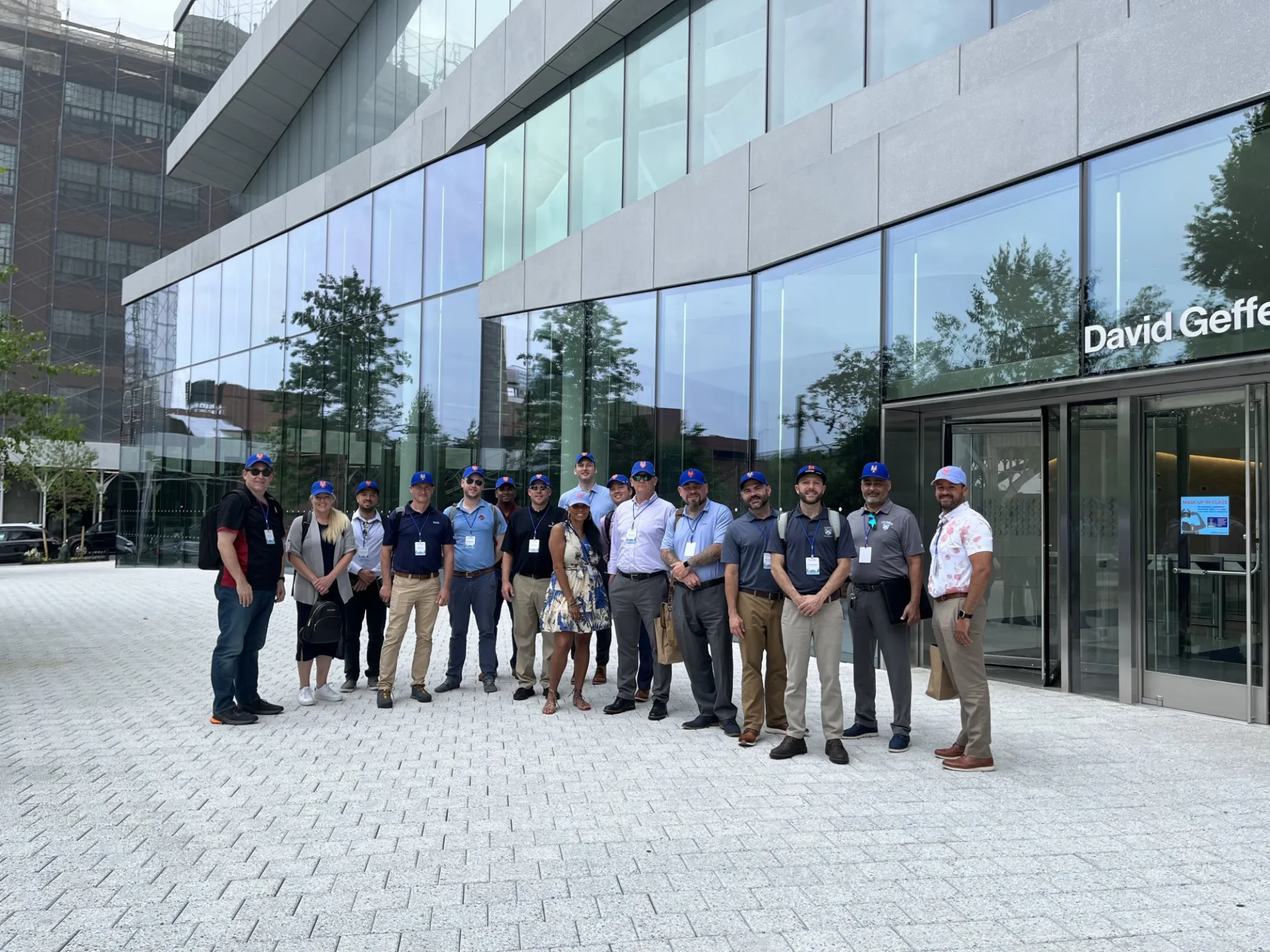 The group stands outside of David Geffen Hall at the Manhattanville Campus