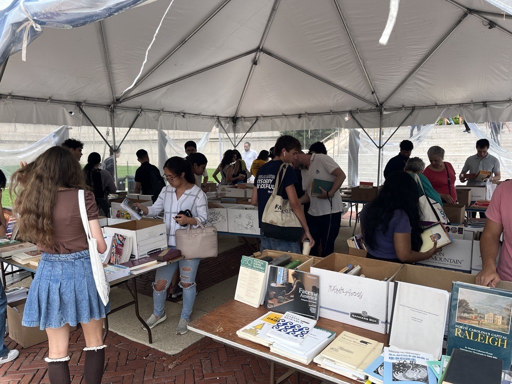 People browse for used books that are laid out on tables under a tent on the Morningside campus.