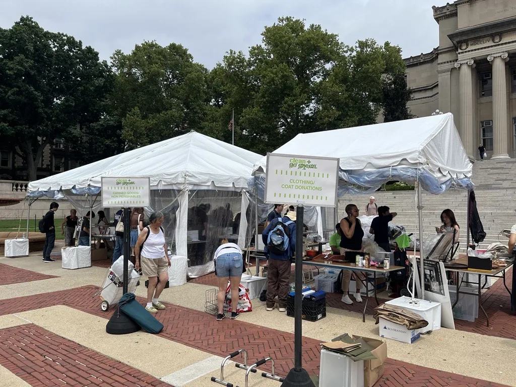 People browse for used books that are laid out on tables under a tent on the Morningside campus. A tent beside the used book tent is set up to take donations of clothing for Columbia Community Service organizations