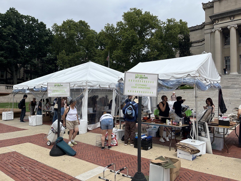 People browse for used books that are laid out on tables under a tent on the Morningside campus. A tent beside the used book tent is set up to take donations of clothing for Columbia Community Service organizations
