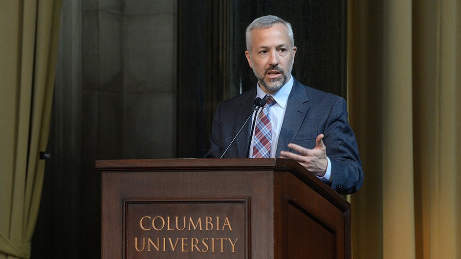 Daniel Zarrilli speaks while standing behind a podium at Columbia University