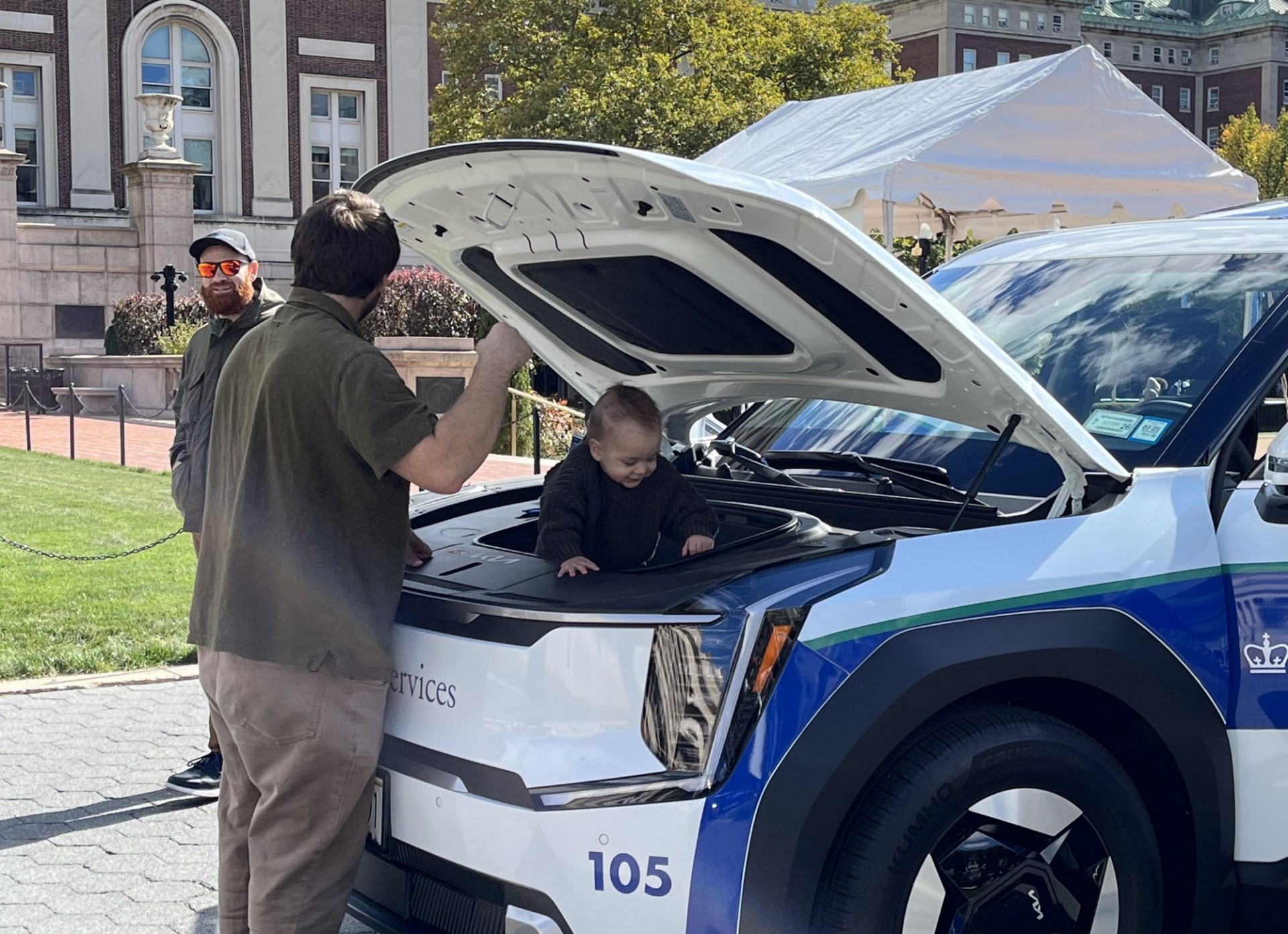 A fleet show participant and child with the Campus Services electric vehicle