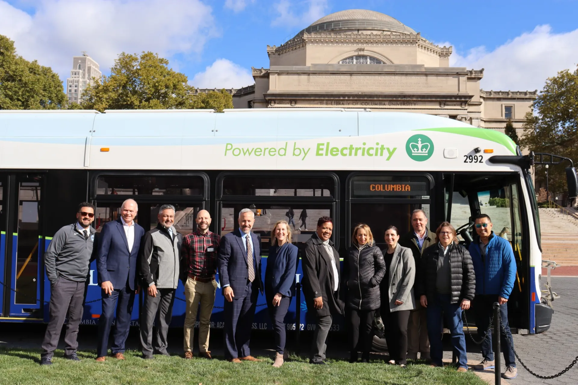 Members of Columbia's Office of Sustainability, Campus Services, and Columbia Transportation stand in front of one of the University's electric buses on College Walk